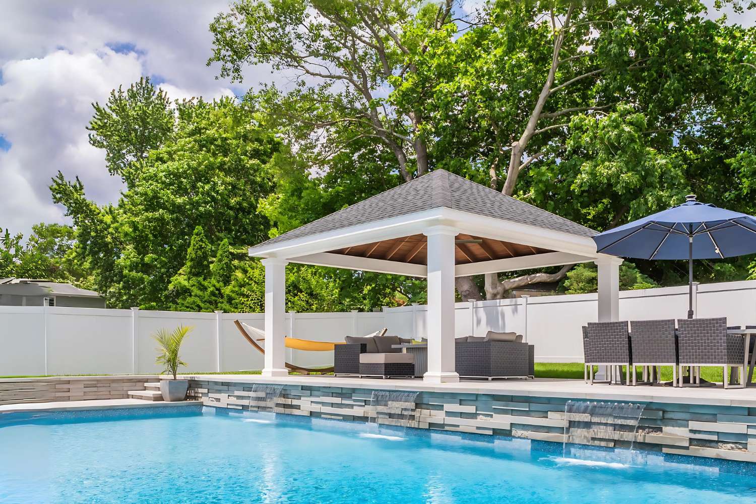 Outdoor Living vinyl pavilion besides pool, seating area, and yellow hammock
