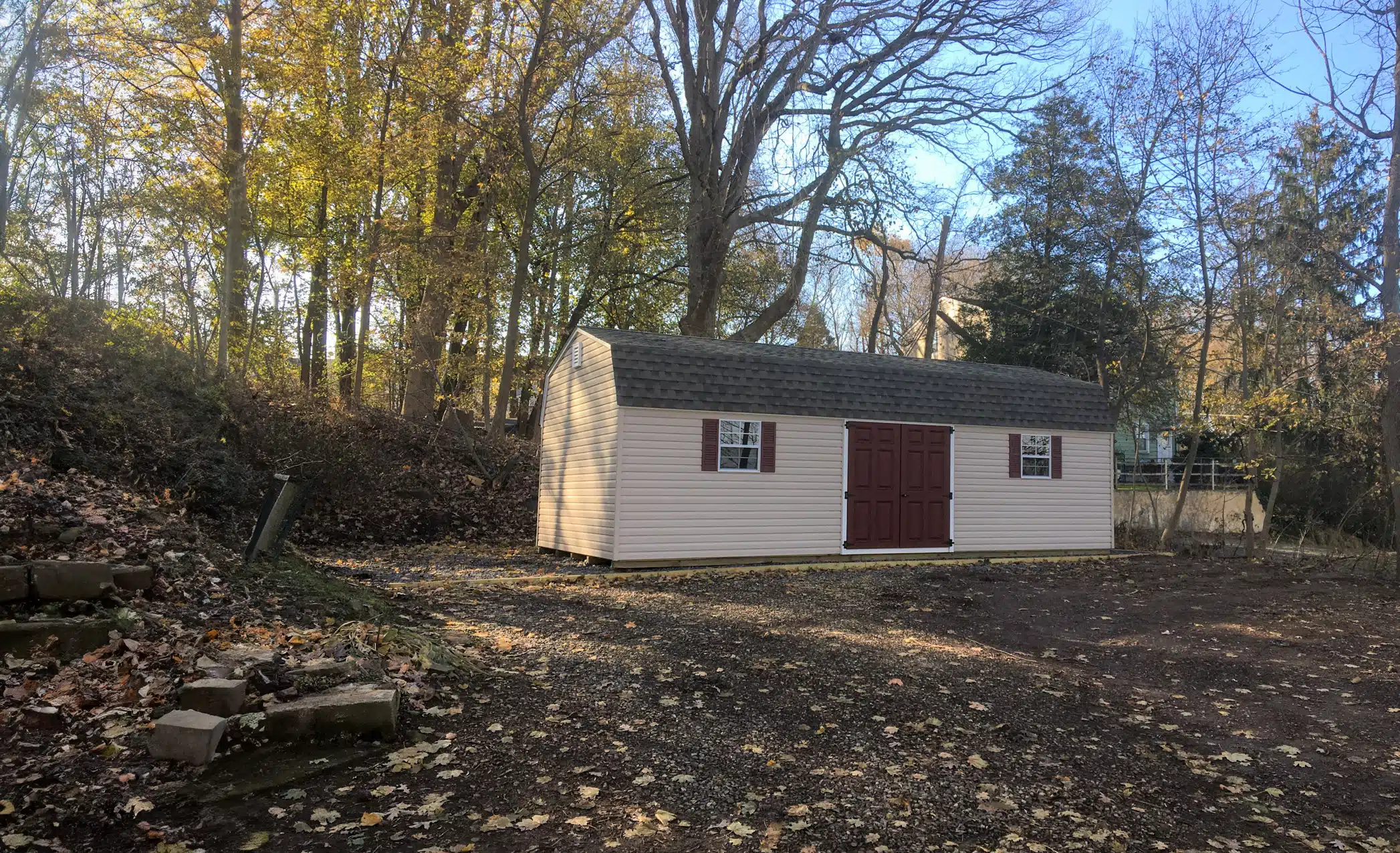 The Standard High Barn Shed 1 Vinyl Standard High Barn Shed in backyard surrounding by trees and autumn leaves