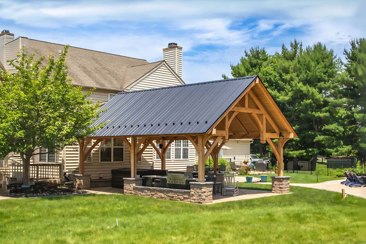 The Denali Pavilion 3 The Denali Timber Frame Pavilion before home with patio and seating area underneath