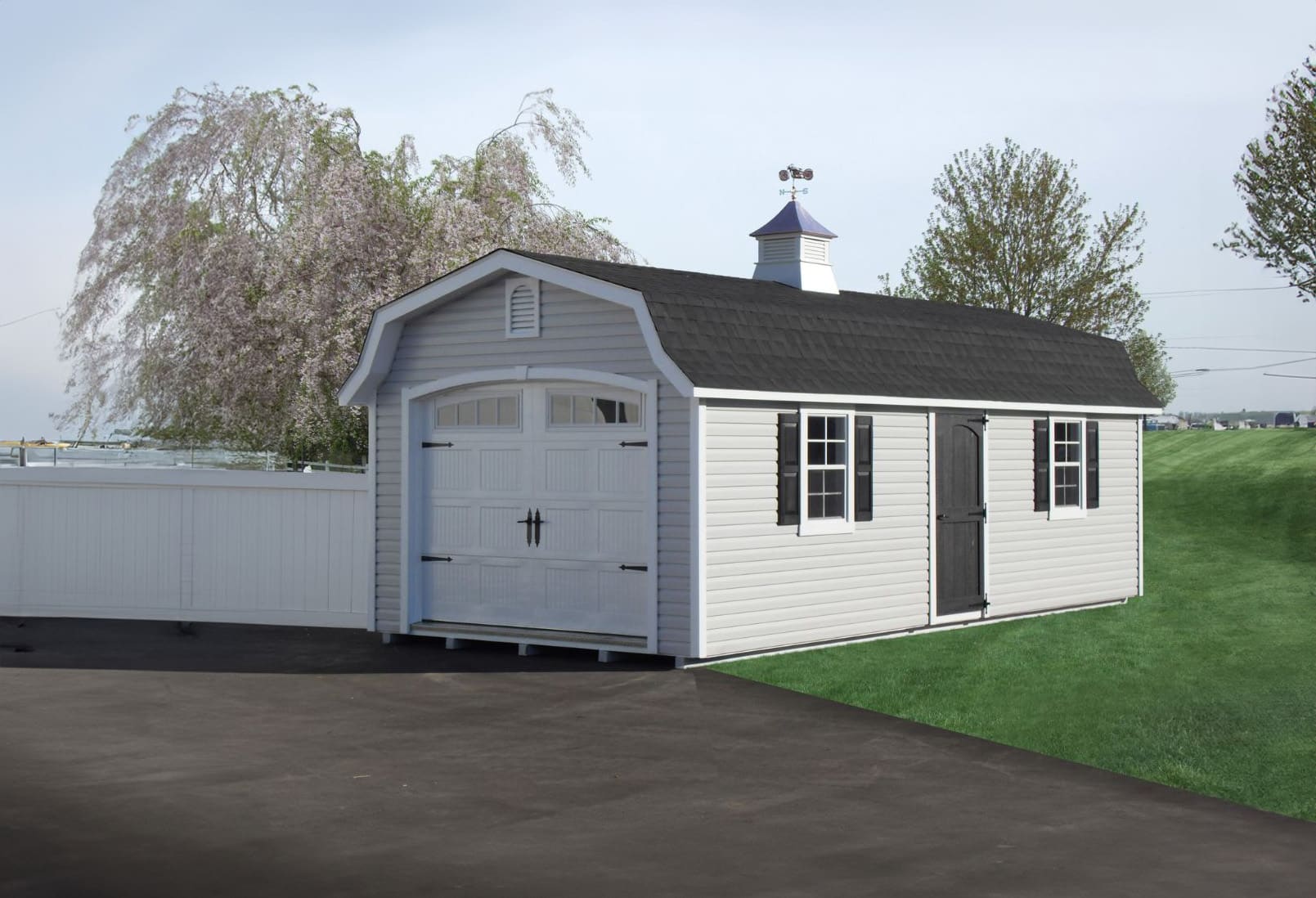 White vinyl designer high barn garage shed in grass and driveway with cherry blossom trees and white fence